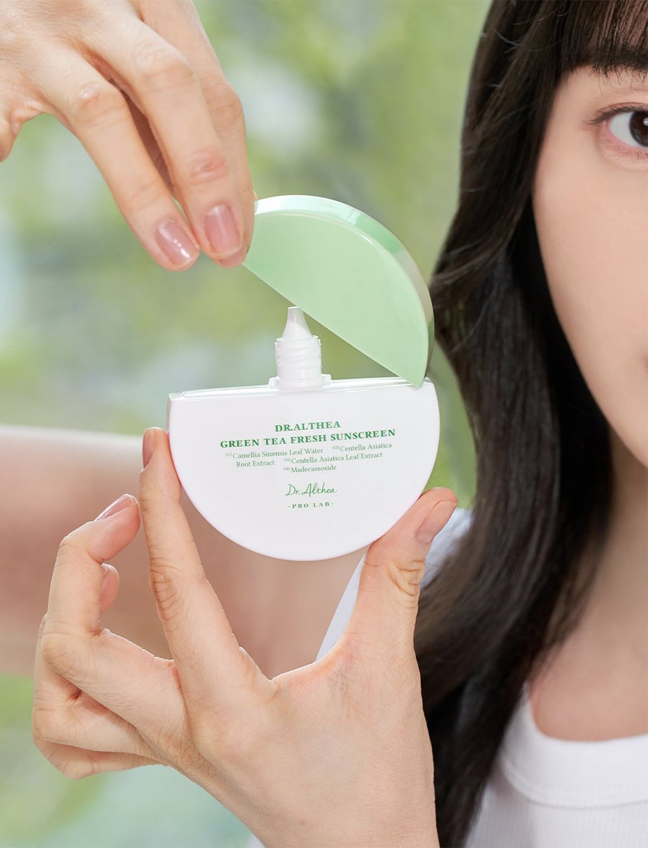 Nahaufnahme einer Hand, die den grünen Deckel der Dr. Althea Green Tea Fresh Sunscreen öffnet, Pumpspender ist sichtbar.