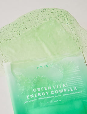 Die AXIS-Y 61% Mugwort Green Vital Energy Complex Sheet Mask läuft aus der Verpackung heraus und die Textur der Maske ist zu sehen.