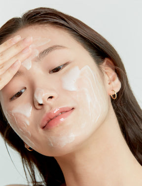 Eine Frau reinigt ihr Gesicht mit dem AXIS-Y Quinoa One Step Balanced Gel Cleanser.
